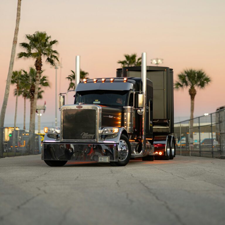 Black semi truck driving at dusk on open highway — owner operator pay guide 2026